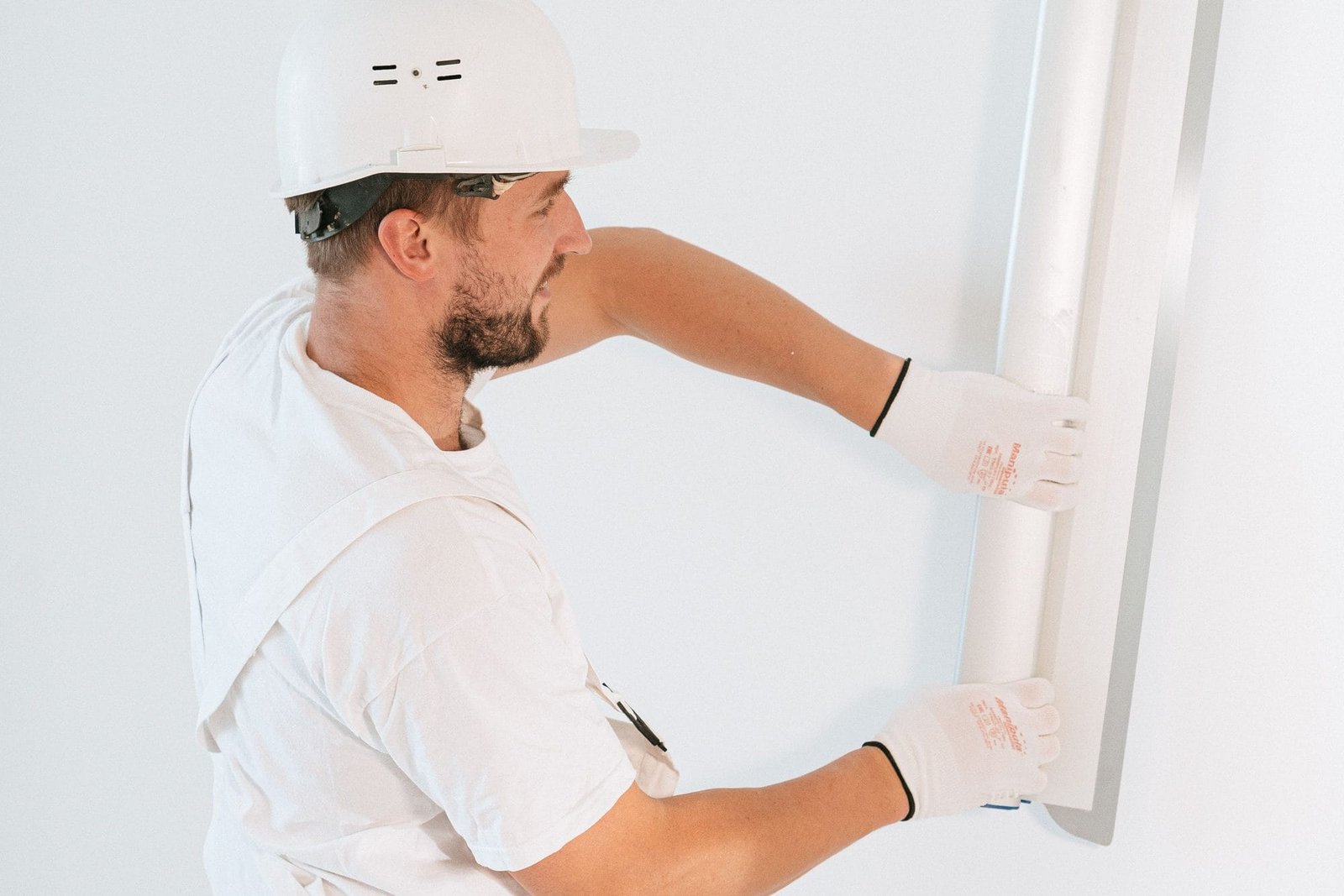 Maler des Malerbetriebs Ziegler bringt eine Leiste an einer weißen Wand an